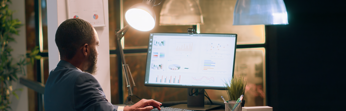 man sitting at a desk looking at data on a computer screen